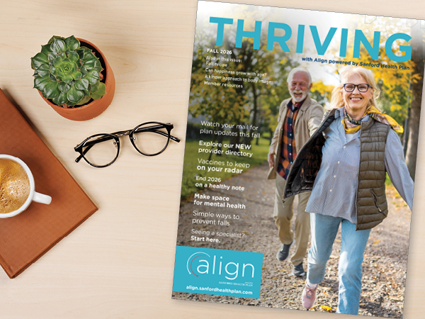 The cover of the Fall 2026 issue of the Thriving Newsletter alongside coffee, eyeglasses, and a potted plant on a table
