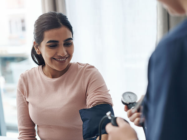 A woman getting her blood pressure checked by a nurse.