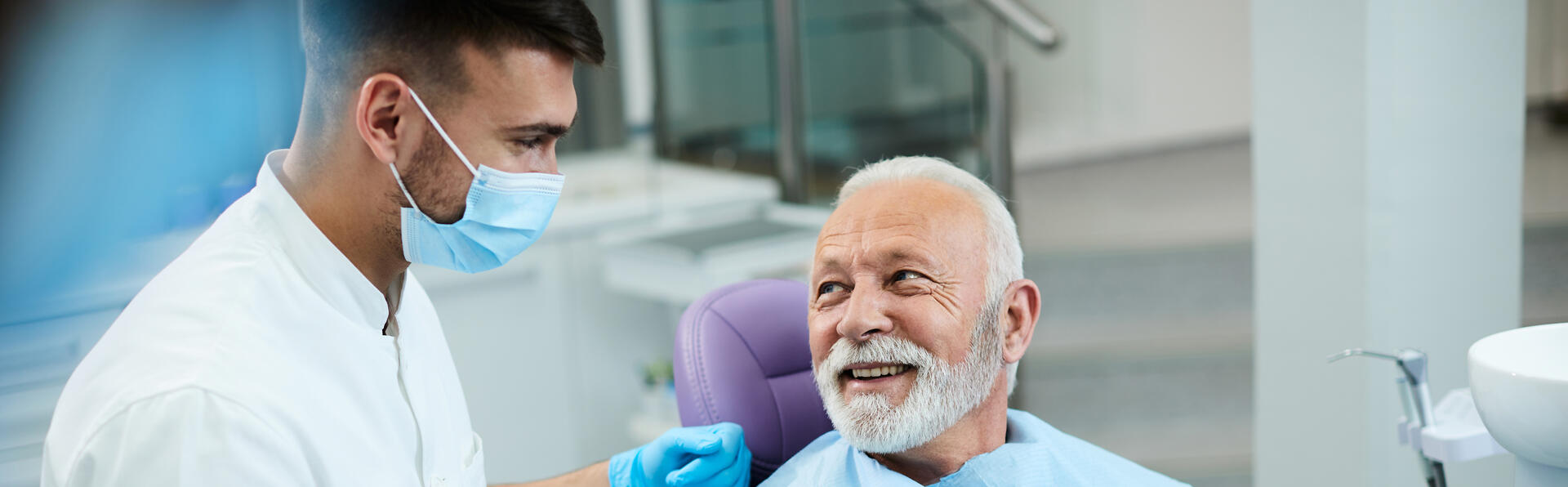 Happy senior man talking to his dentist while being satisfied with dental procedure at dentist's office.