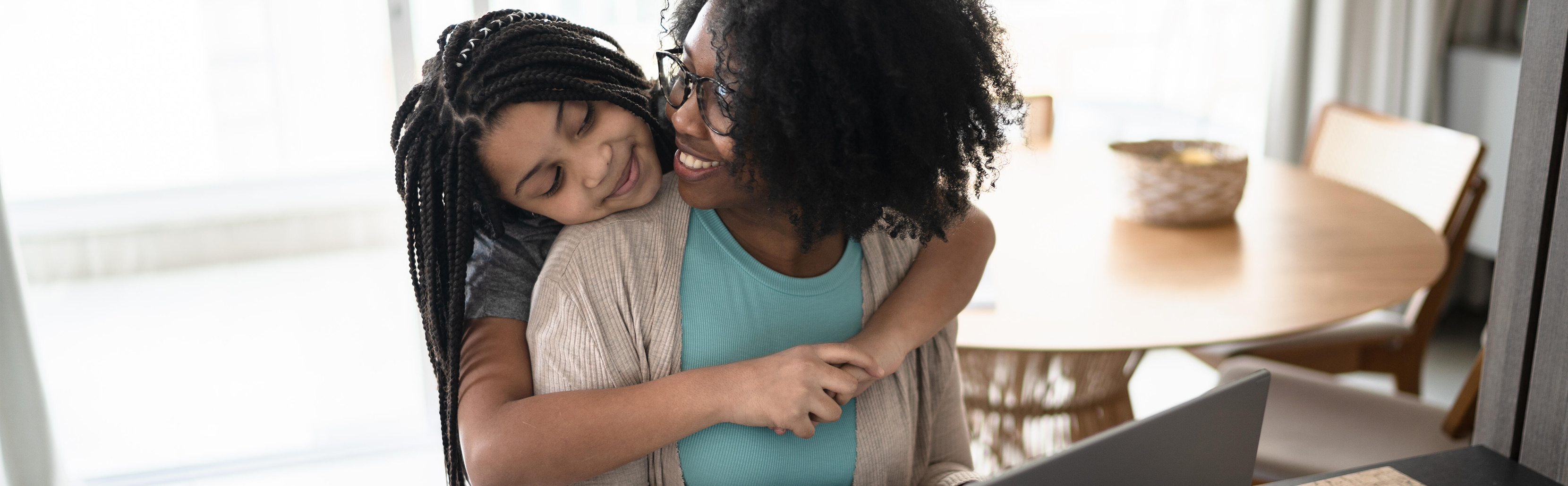 Young girl hugging her mother while she works from home