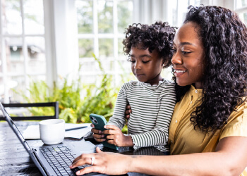Mother trying to work on laptop while her young daughter is distracting her