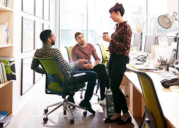Three coworkers in a laid back office space discussing work