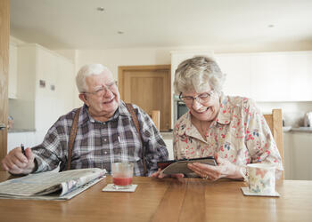 Elderly man and woman looking at a newspaper