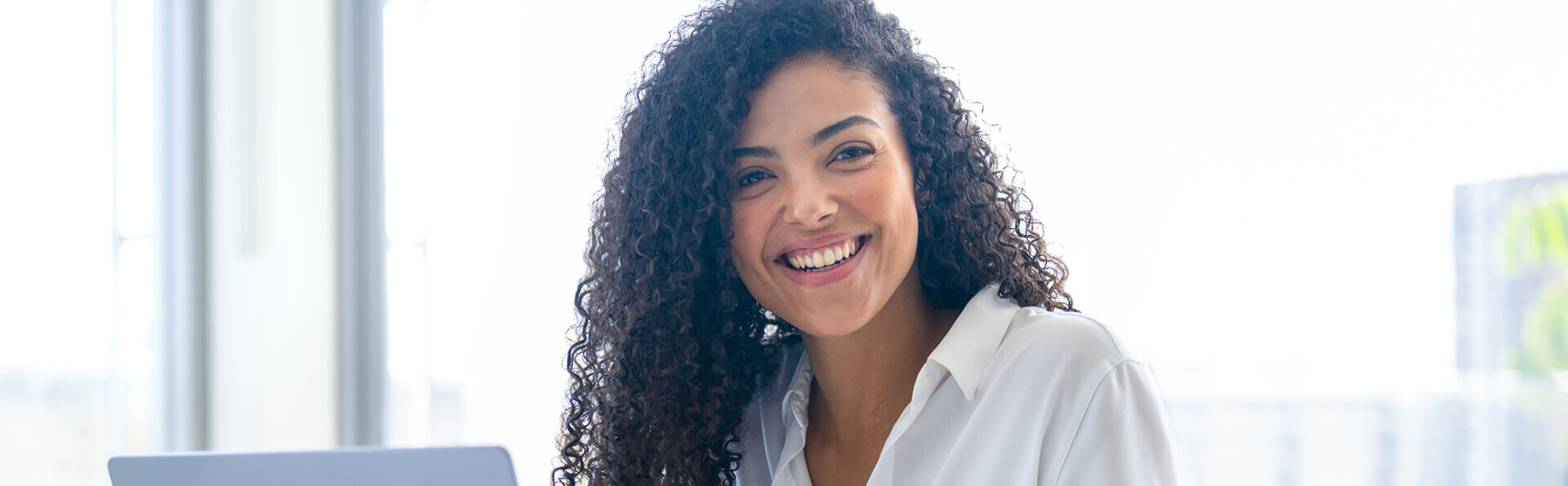 Young businesswoman grinning with an open laptop in front of her
