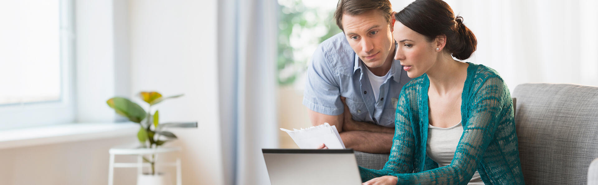 A woman and man looking at papers and their computer comparing notes.