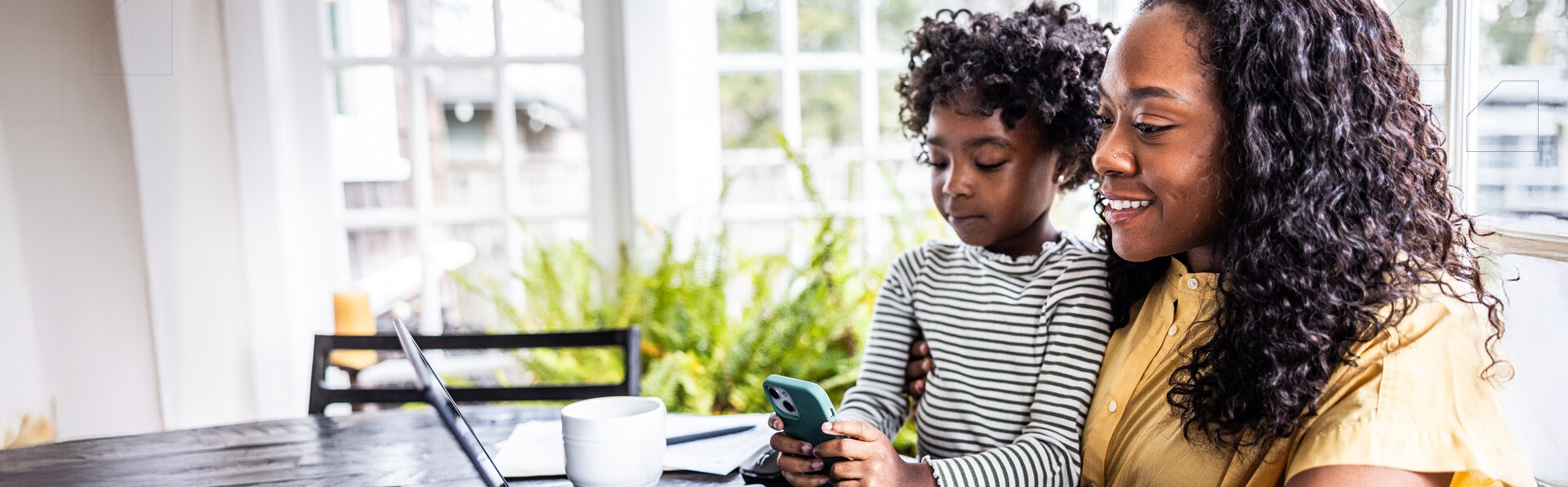 Mother trying to work on laptop while her young daughter is distracting her