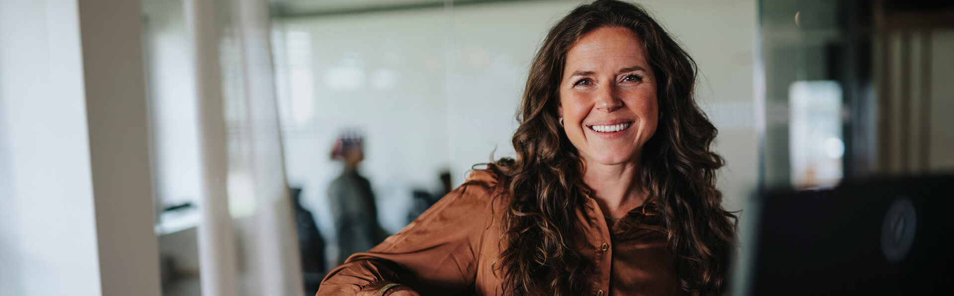 A professional woman in her office at work smiling.