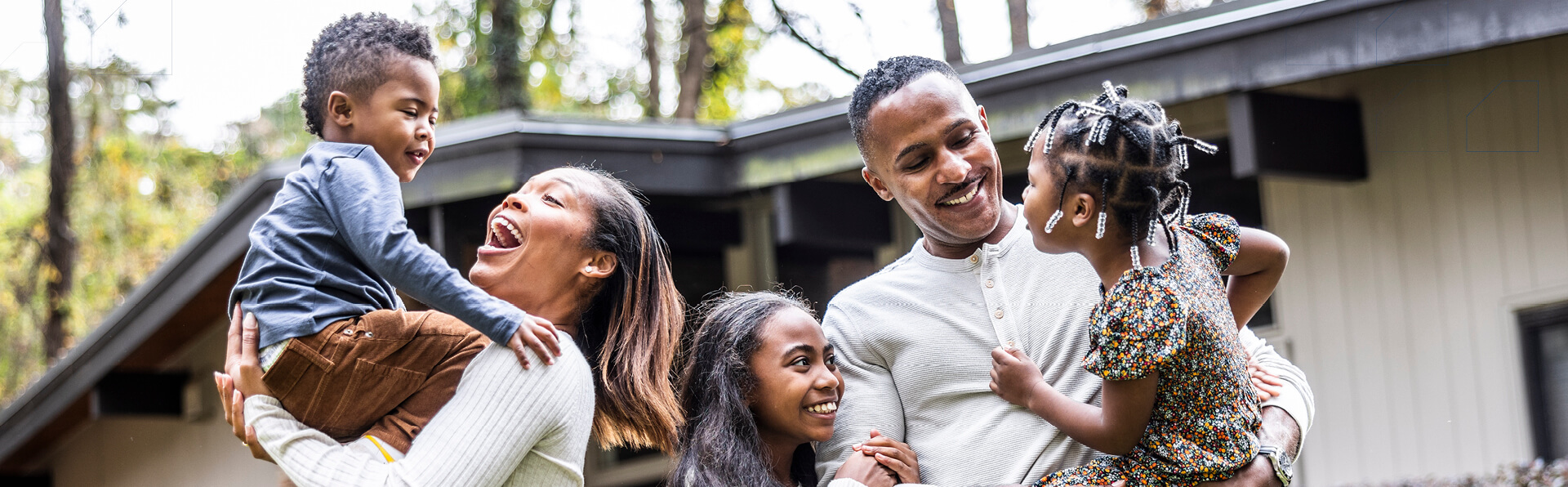 Portrait of family with young children in front of suburban home