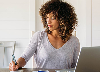 Woman writing notes at her desk